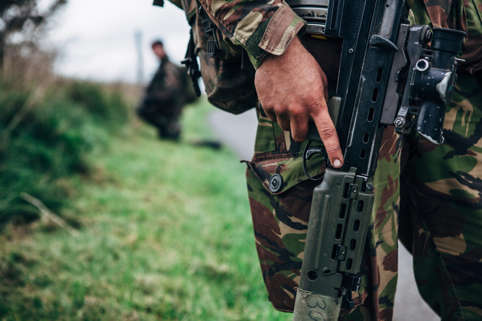 Close up view of a solider holding an L85A2 british assault rifle on a military training exercise in a rural location.